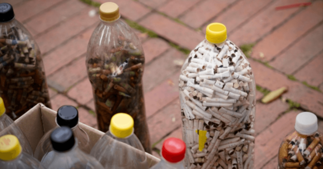 Foto que muestra una botella llena de colillas de cigarrillo 