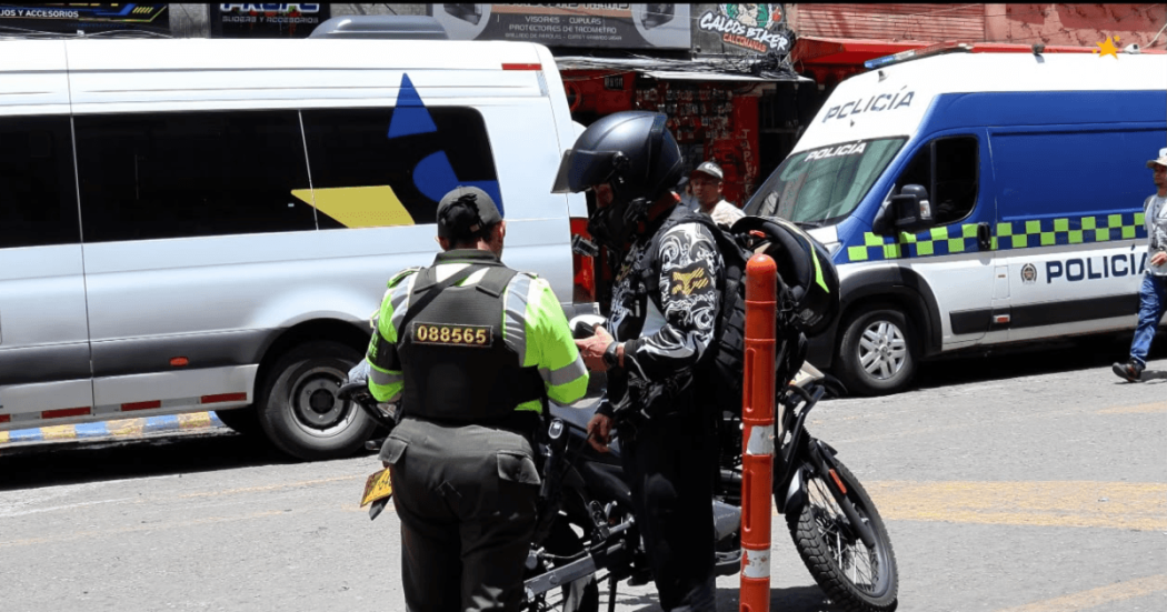 Policía registrando a una persona y verificando su motocicleta.
