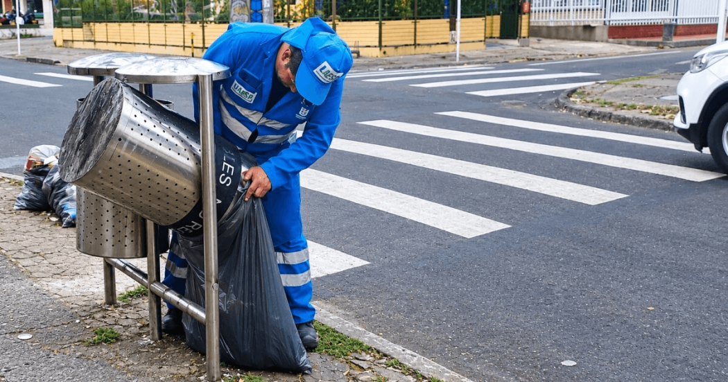Foto que muestra una persona con el uniforme de LIME haciendo aseo en una caneca para basuras