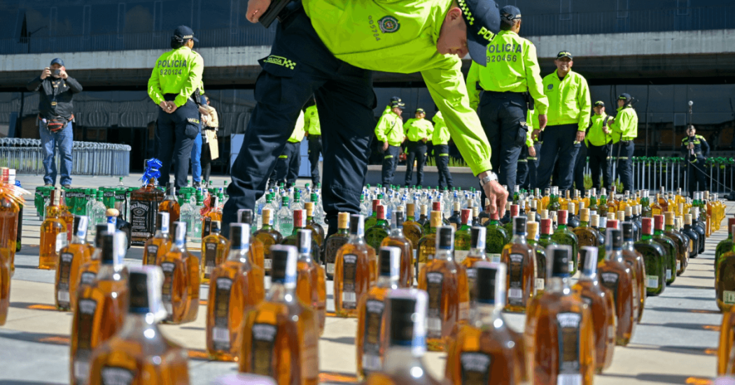 Foto de policías exponiendo en el piso botellas incautadas.
