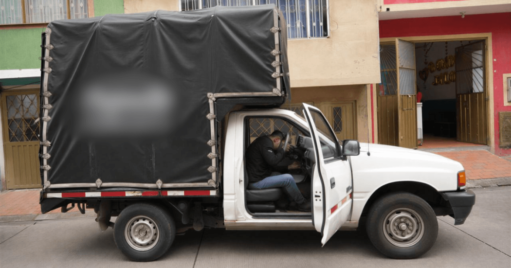 Camioneta del programa Foncarga de Bogotá estacionada con la puerta del conductor abierta y un módulo cubierto instalado en la parte trasera, frente a edificaciones urbanas.