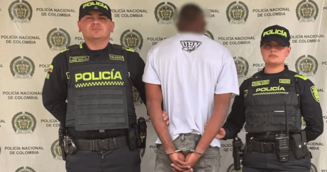 Foto de un hombre capturado en medio de dos policías.