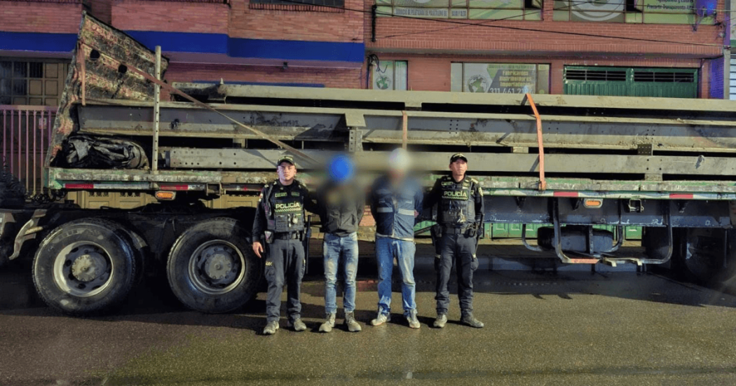 Dos capturados en medio de dos Policías. Detrás está el camión con los 11 rieles incautados.