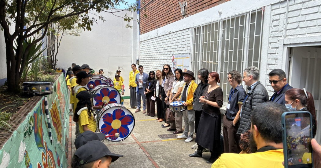 Grupo de personas de una entidad de vocación social dan la bienvenida a invitados especiales con una muestra cultural usando instrumentos musicales. 