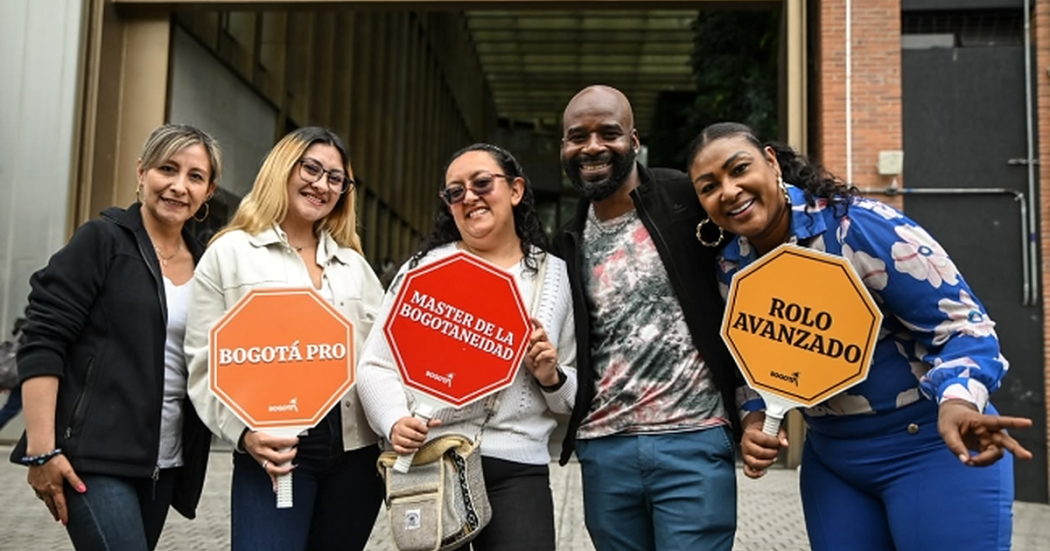 Foto de grupo de personas con carteles llamativos en torno a los diferentes gentilicios de los habitantes de Bogotá.