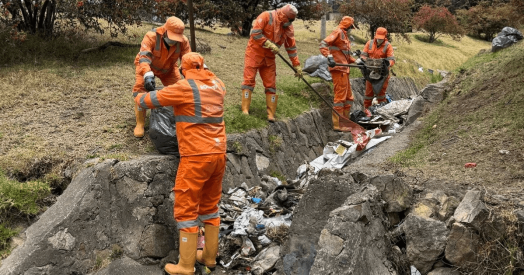 Foto que muestra personas con el uniforme de Aguas Bogotá limpiando una quebrada