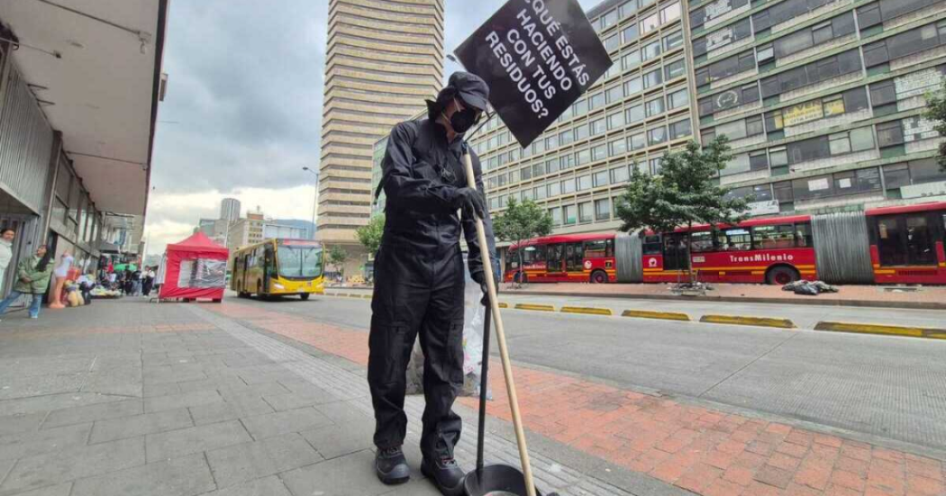 Imagen de un hombre vestido con overol azul recogiendo los residuos de la calle. De fondo se ve la carrera Décima de Bogotá.