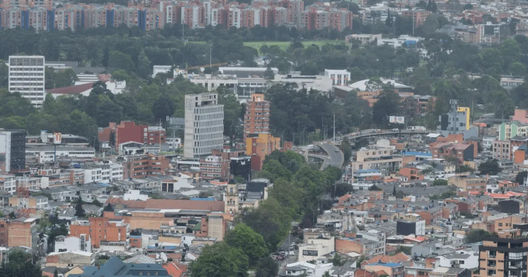 Vista panorámica de Bogotá con edificaciones residenciales y comerciales de diferentes alturas, avenidas arboladas y sectores urbanos que se extienden hacia el horizonte.
