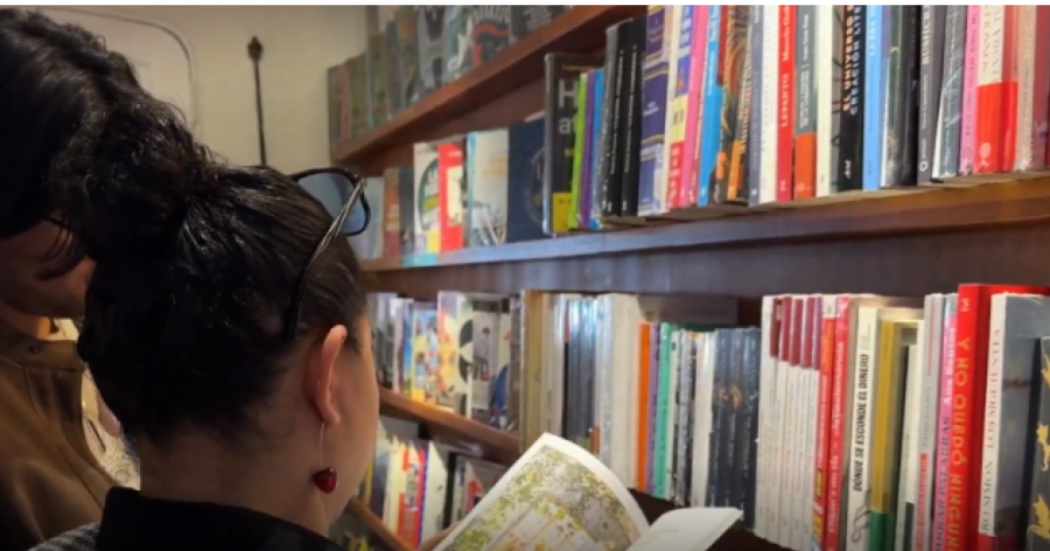 Imagen d eun holbre y una mujer leyendo un libro en una biblioteca.