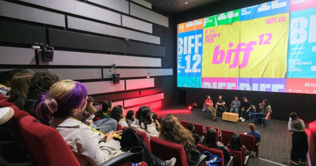Imagen de varias personas en un escenario donde se ve una gran pantalla en la que se proyecta publicidad del BIFF 12.