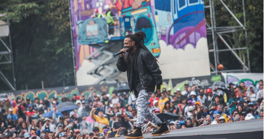 Imagen de un artista en la tarima de Hip Hop al Parque de fondo se ven muchos asistentes.