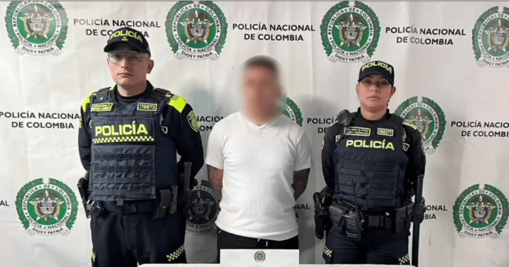 Foto de un hombre capturado en medio de dos policías.