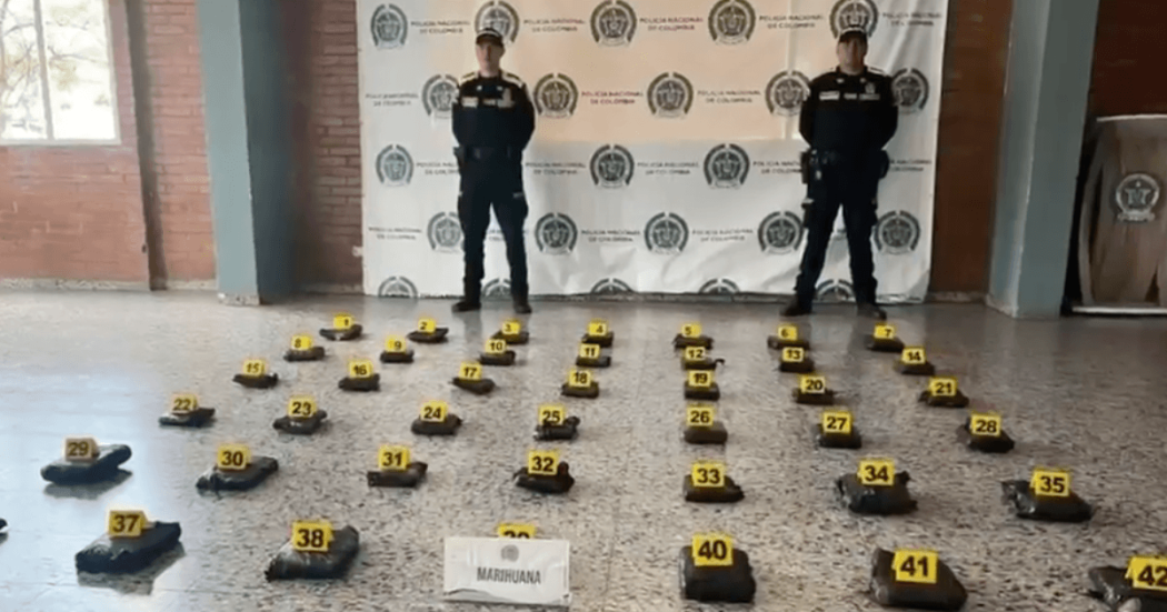 Foto de dos policías frente a paquetes de mariuana incautados en el aeropuerto.