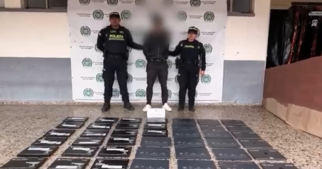 Foto de una persona capturado, dos policías y computadores recuperados