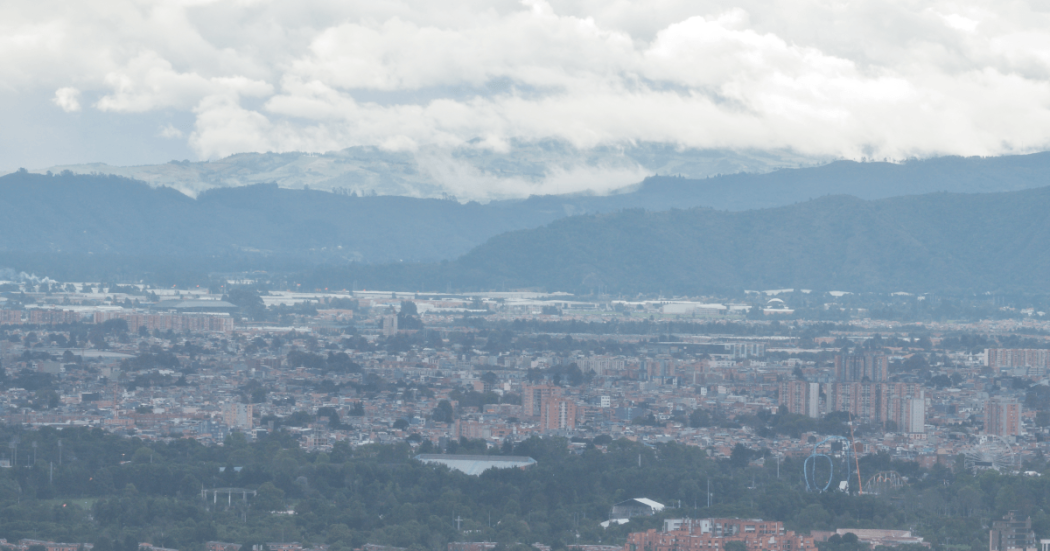 Vista panorámica de Bogotá desde un punto elevado. En primer plano se observan edificaciones urbanas y, al fondo, una cadena montañosa bajo un cielo con abundante nubosidad.