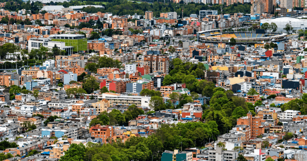 Foto panorámica de una amplia zona urbana con un estadio, edificios, casas y áreas verdes.