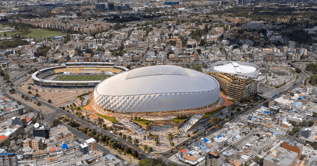 Vista aérea de un estadio cubierto de forma ovalada, rodeado por vías, edificaciones y zonas urbanas densamente construidas.