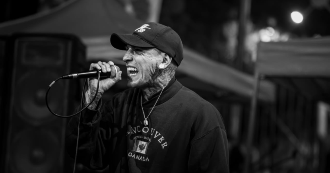 Foto de Kain Anmistía cantando con una gorra oscura