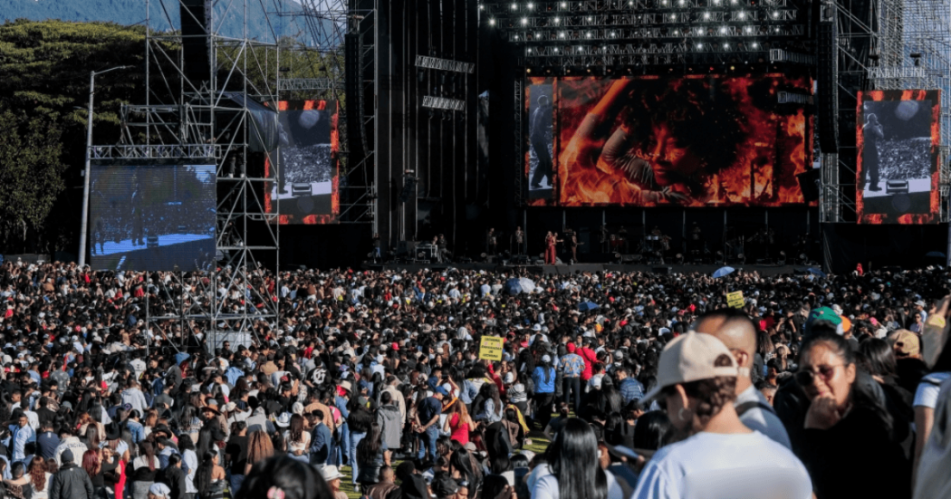 Asistentes en Bogotá reunidos frente a un escenario principal durante un concierto masivo al aire libre, con pantallas gigantes, estructuras de iluminación y equipos de sonido en el parque Simón Bolívar donde se realizará Rock al Parque 2026.