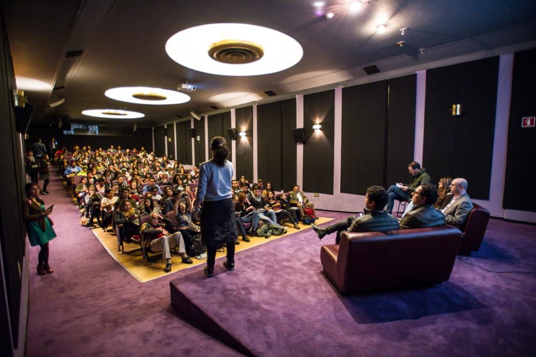 Un auditorio donde varias personas miran a un hombre de pie en el escenario