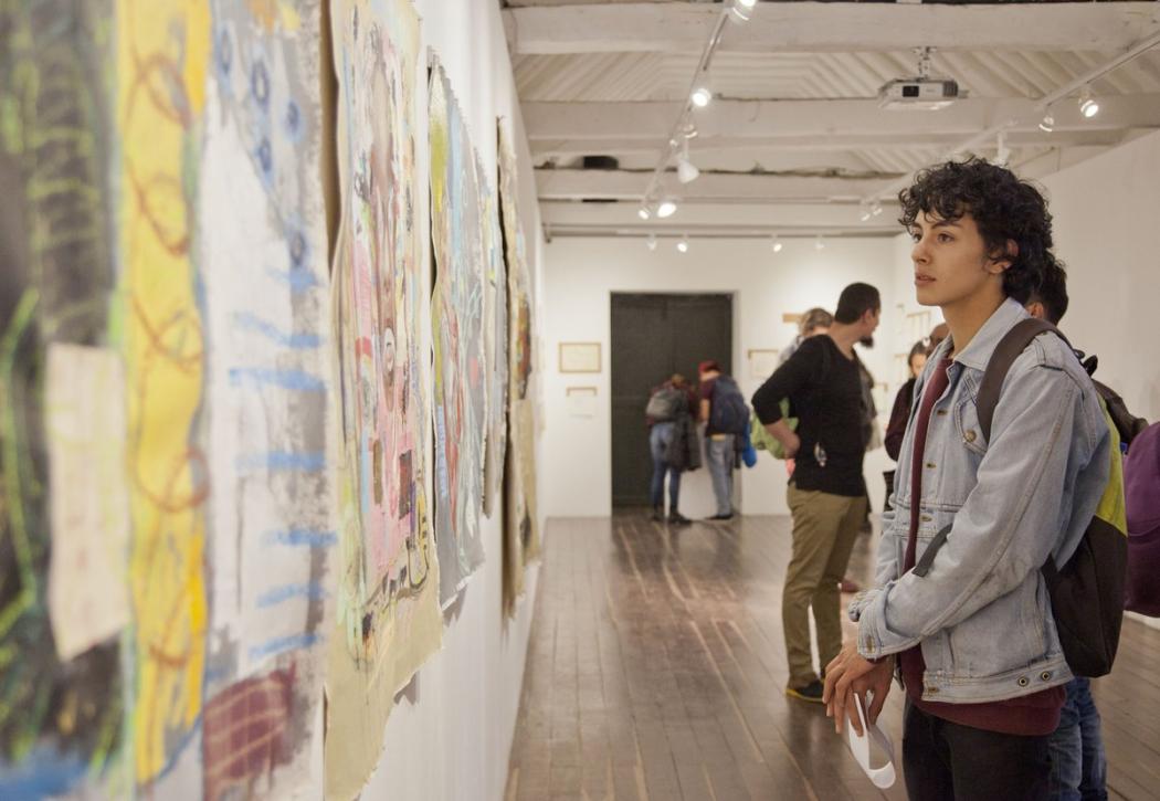 Un joven observando una pintura en la pared 