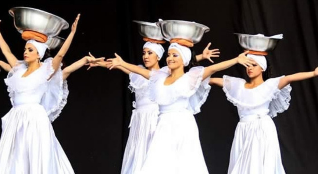Cuatro mujeres hacen una presentación de danza vestidas con trajes típicos.