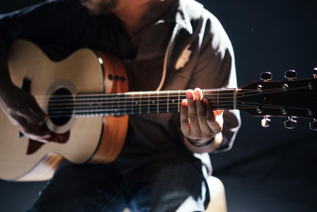 Un hombre con una guitarra acústica tocando varias canciones 