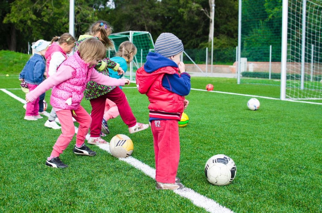 Varios niños pequeños jugando fútbol en una cancha de fútbol