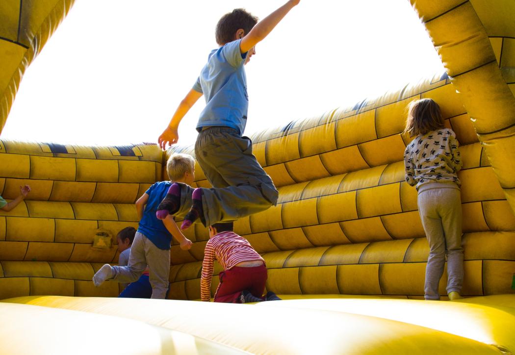 Unos niños jugando en un juguete inflable amarillo, saltando y corriendo 