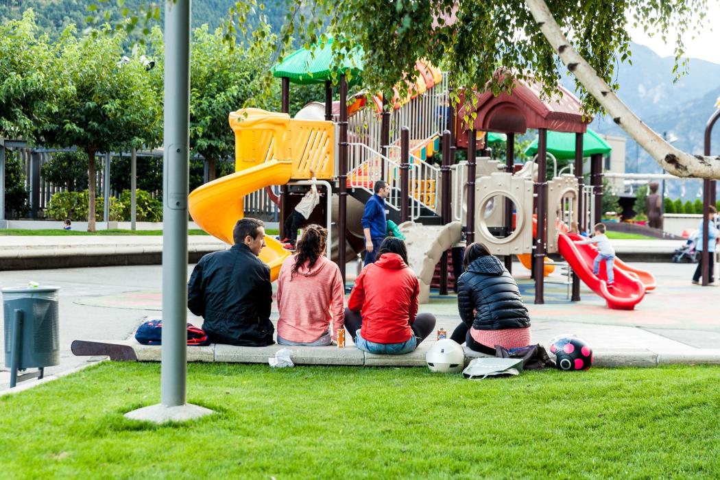 Un parque con varios padres vigilando a sus niños en un juego de parque 