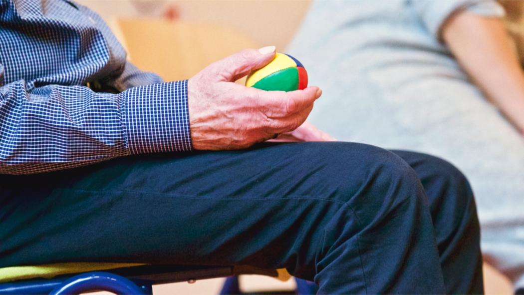 Un señor mayor sosteniendo una pelota de colores
