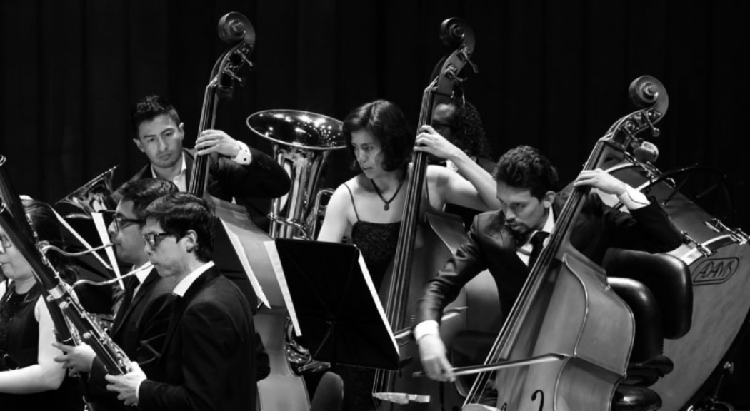 Foto en blanco y negro de un grupo de jóvenes de la Banda Filarmónica Juvenil interpretando instrumentos de cuerda.