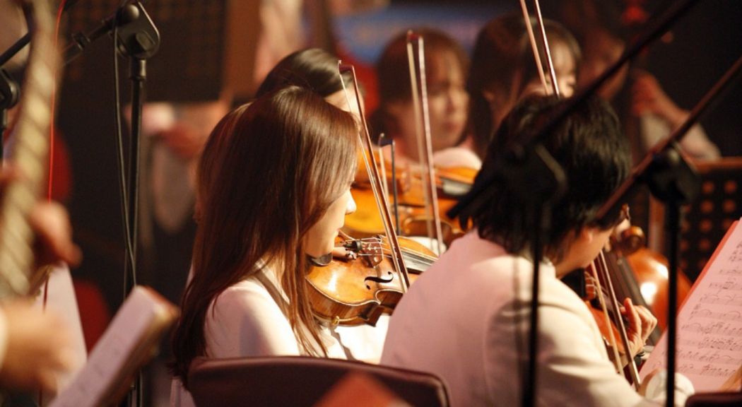 Foto ligeramente desenfocada de un grupo de jóvenes interpretando el violín.