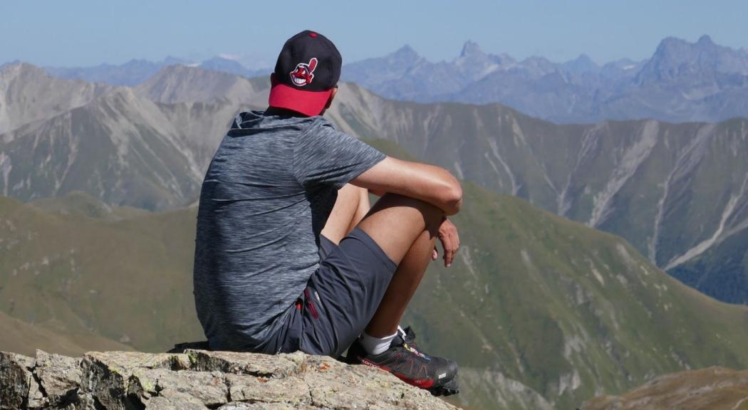 Foto de stock de un hombre joven mirando al horizonte lleno de montañas. 