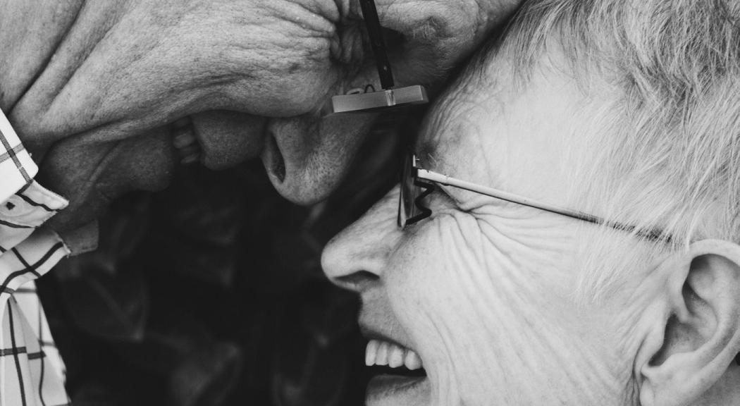 Foto en blanco y negro de stock. Una pareja de ancianos se acerca a darse un beso.