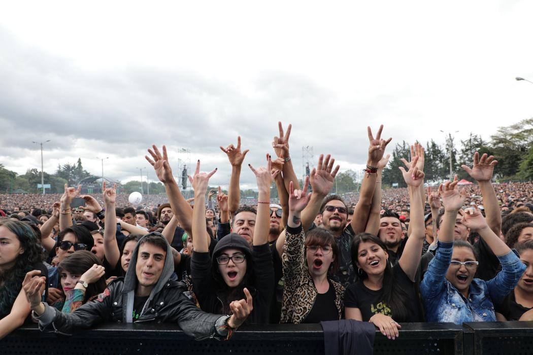 Varias personas en un concierto con las manos alzadas y gritando emocionadas 