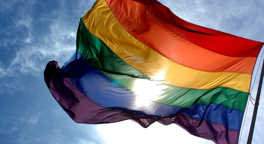 Bandera LGBTI en varios colores ondea contra el sol.