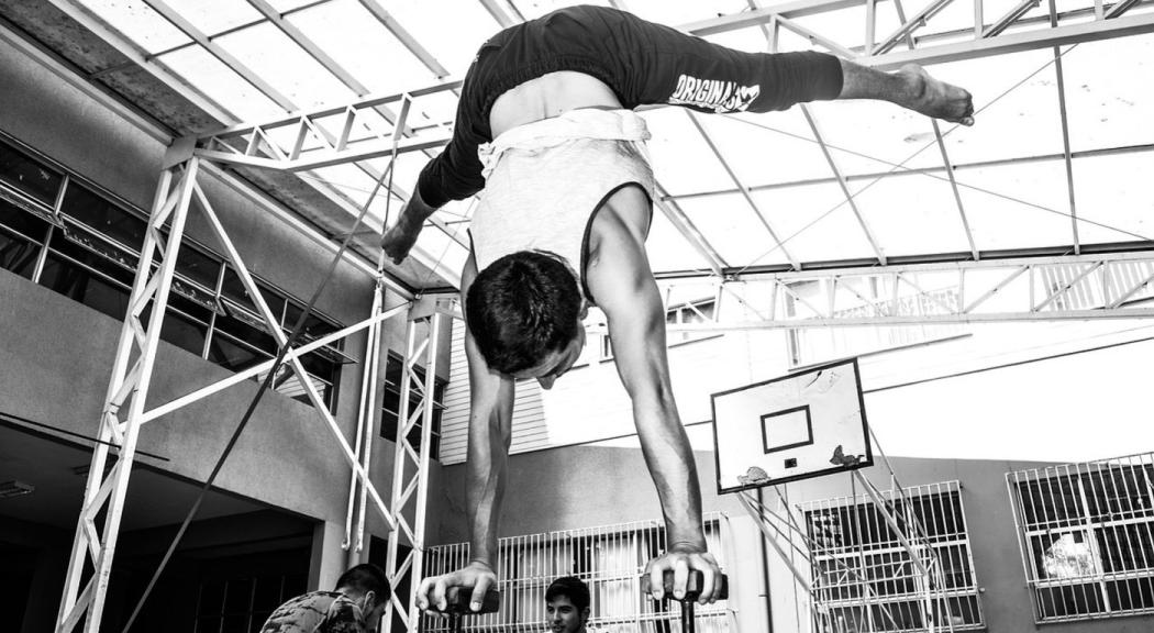 Foto en blanco y negro, un joven hace acrobacias.