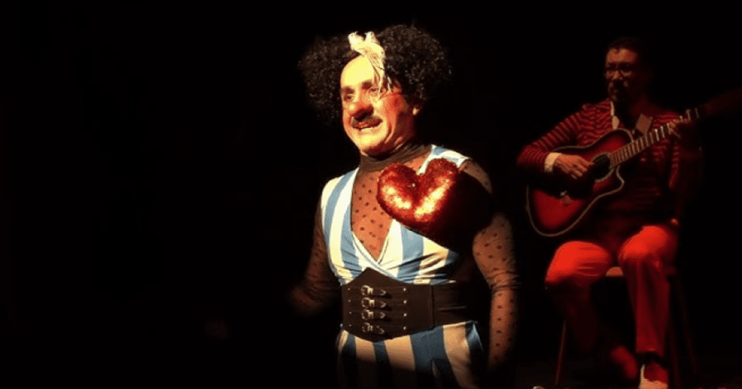 Imagen con fondo negro con un payaso y un hombre tocando guitarra