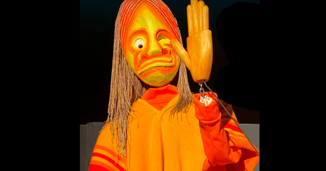 Imagen de un títere amarillo en fondo negro.