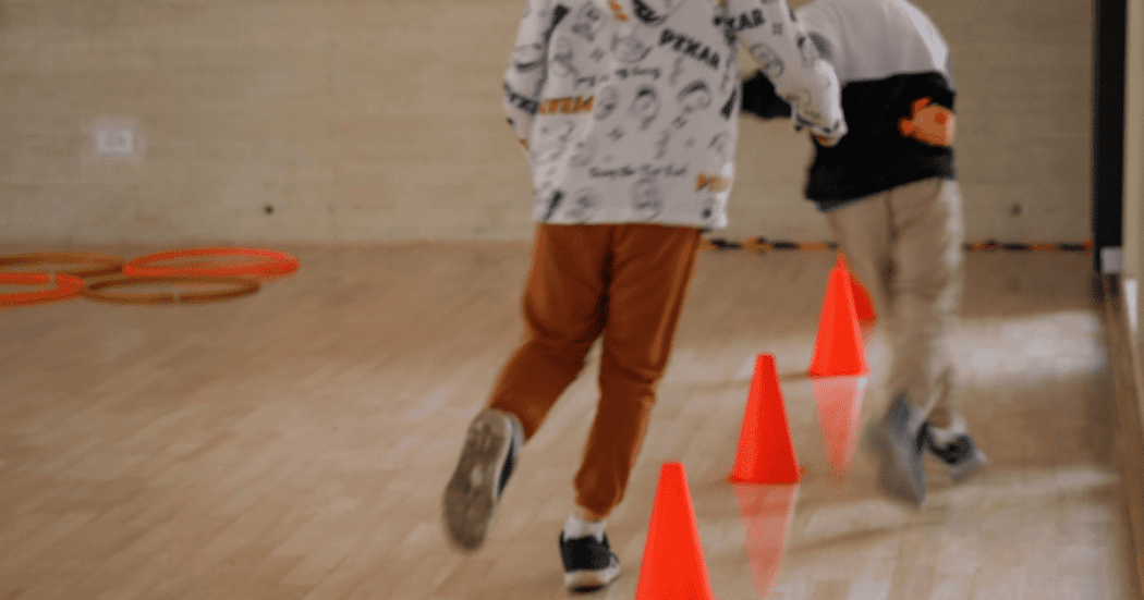Imagen de dos niños juagando con conos plasticos de color naranja ubicados en el piso