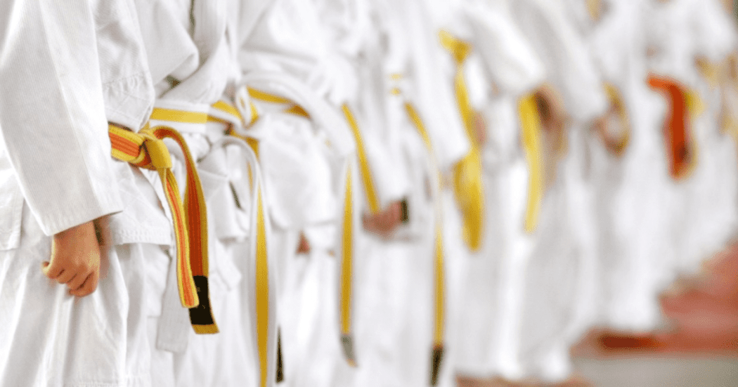 Imagen de personas en fila vestidos con traje de karate y cinturon amarillo