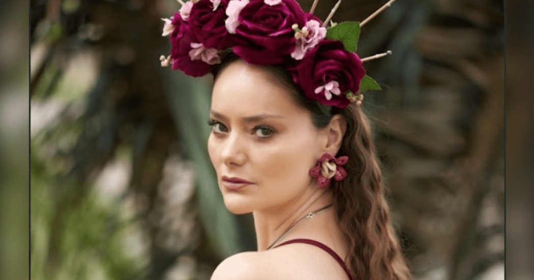 Imagen de la cantante María Multa que porta en su cabeza un tocado de grandes flores color vinotinto y rosado