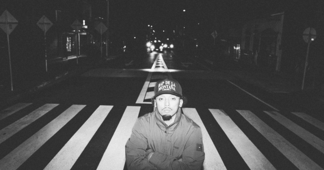 Imagen de hombre jóven en la noche en una calle donde al fondo se evidencia señalización en el piso