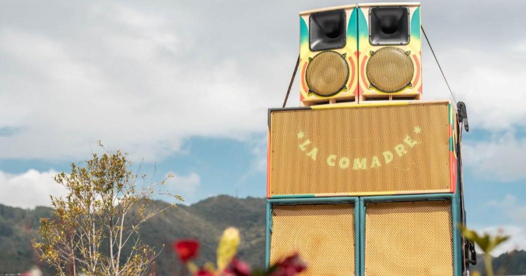 Imagen de parlantes grandes con letras de La Comadre en un paisaje