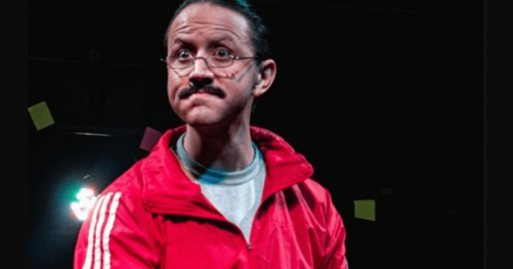 Imagen de hombre mayor que usa gafas y chaqueta roja con cara de angustia con un fondo oscuro