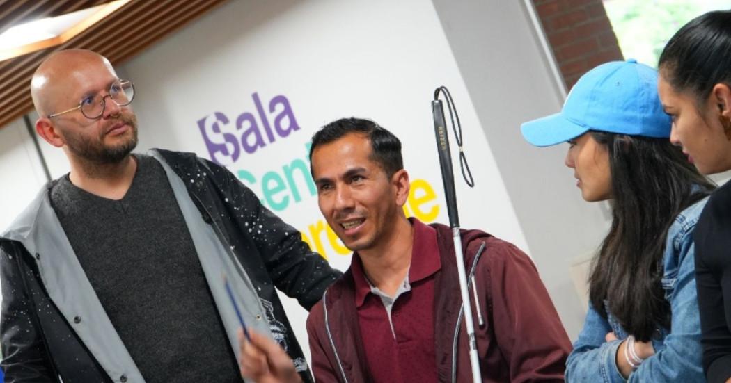 Imagen de cuatro personas, una de ellas con bastón por discapacidad visual