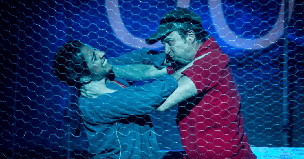 Imagen de dos hombres detrás de una cerca peleando, se aprecia como se aprietan el cuello