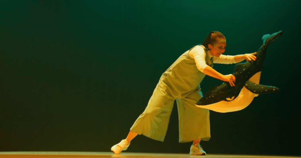 Imagen de una niña vestia de blanco jugando con una ballena yubarta