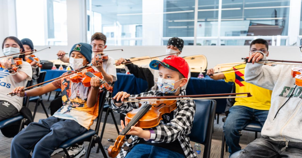 Foto de niños y niñas participan en una clase de violín